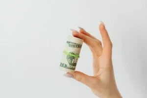 A hand holding round folded  currency notes 